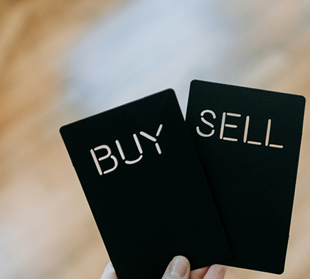 Une main tenant deux cartes Buy et Sell